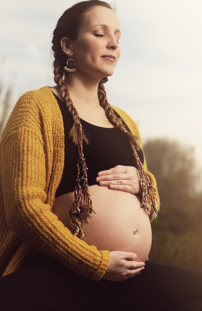 Schwangere meditiert mit den Händen auf ihrem Bauch