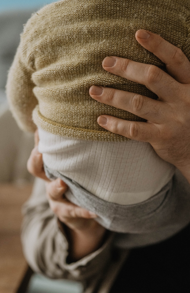 Vater hält seinen Sohn im Arm, zu sehen sind der Rücken des Babys und die Hände des Vaters